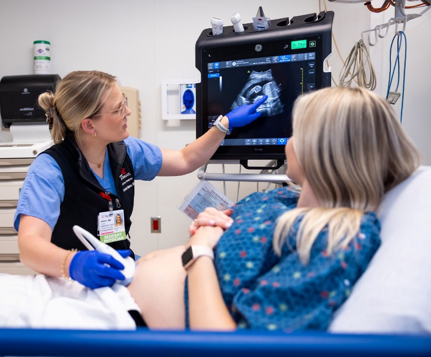 Resident performing ultrasound on pregnant patient