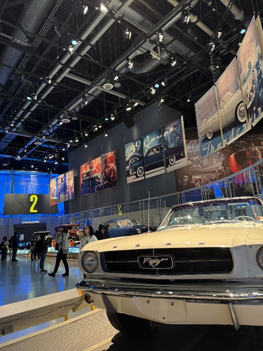 close up of ford mustang in a museum with other cars and people in the background