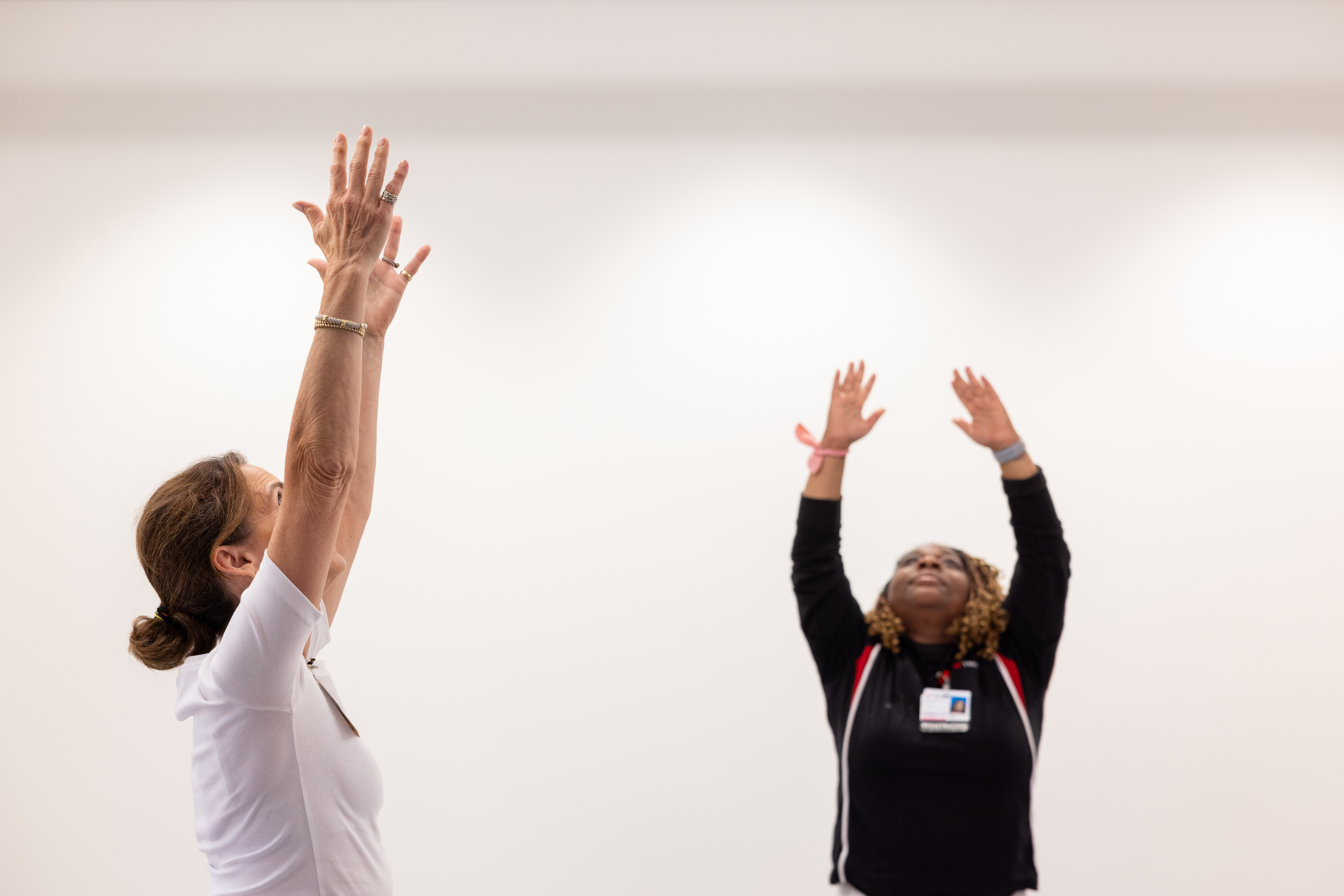 BCHC Tina Yoga two people performing yoga reaching hands up