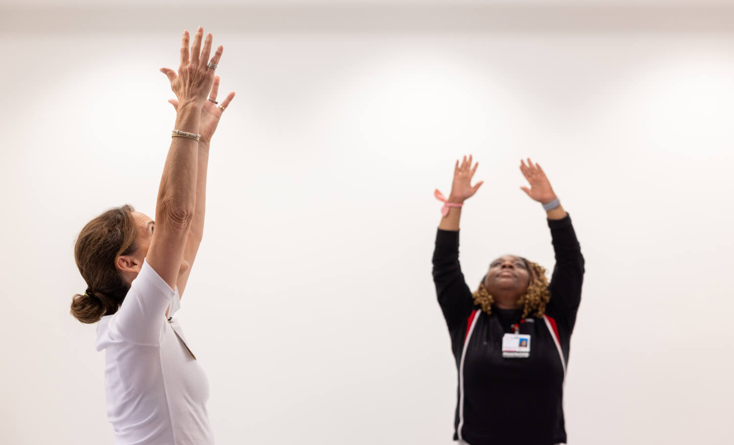 two people performing yoga reaching hands up