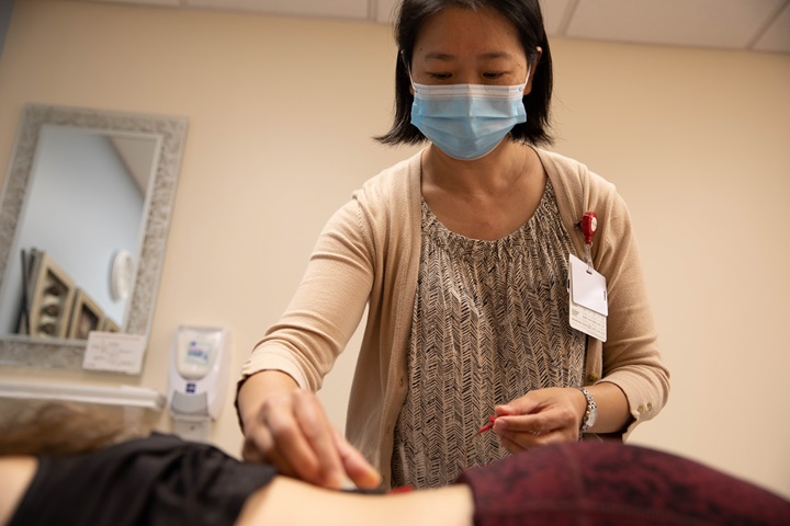 acupuncturist performing acupuncture on patient