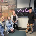 people in posing in front of the create culinary studio sign