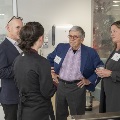 A group of four people mingling with drinks in their hands