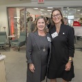Two women pose together with a kitchen in the background