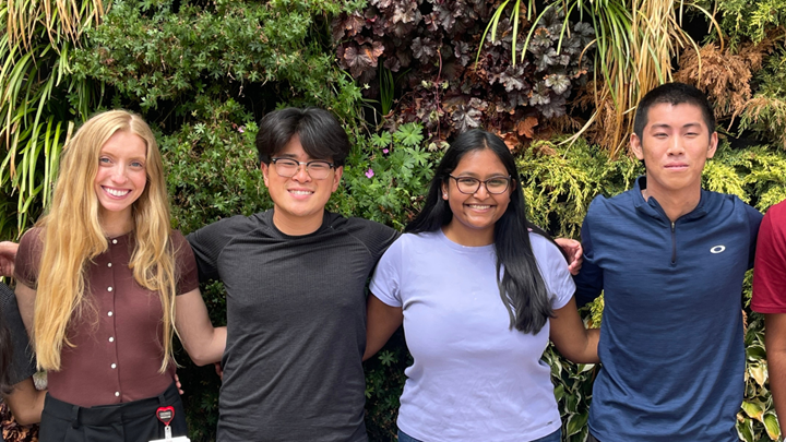 four research students standing in front of living wall