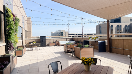 view of the osher wellness suite rooftop healing garden including potted plants, living wall, and seats and tables, looking into the city