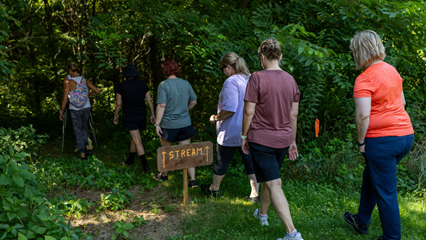 a group of people walking into the forest next to a sign with the word stream
